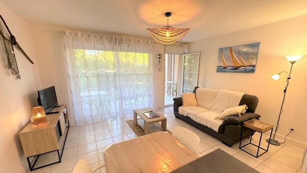 A modern living room with a sofa, a dining table, and a TV. - L'appartement Pins D97 (CAPBRETON)