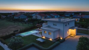 A modern two-story house with a swimming pool, surrounded by a well-maintained lawn and a view of neighboring houses. - Stunning home in Pula (Pula)