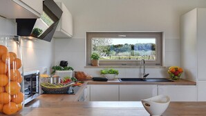 A modern kitchen with a large window, wooden countertops, and a variety of fresh produce and fruits. - Stunning home in Pula (Pula)