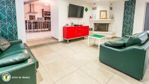 Una sala de estar con un sofá verde, un mueble rojo y un televisor.