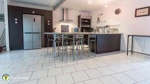 Una cocina moderna con una isla central, electrodomésticos integrados y un comedor con sillas.