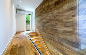 A modern interior with a wooden floor and a glass railing on a staircase.