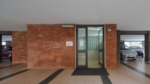 A parking garage with a brick wall, a glass door entrance, and cars parked inside.