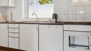 Eine moderne Küche mit weißen Schränken, einem eingebauten Geschirrspüler und einem Backofen.
