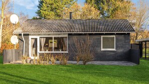 Ein modernes Haus mit dunklem Dach, großen Fenstern und einem kleinen Garten.