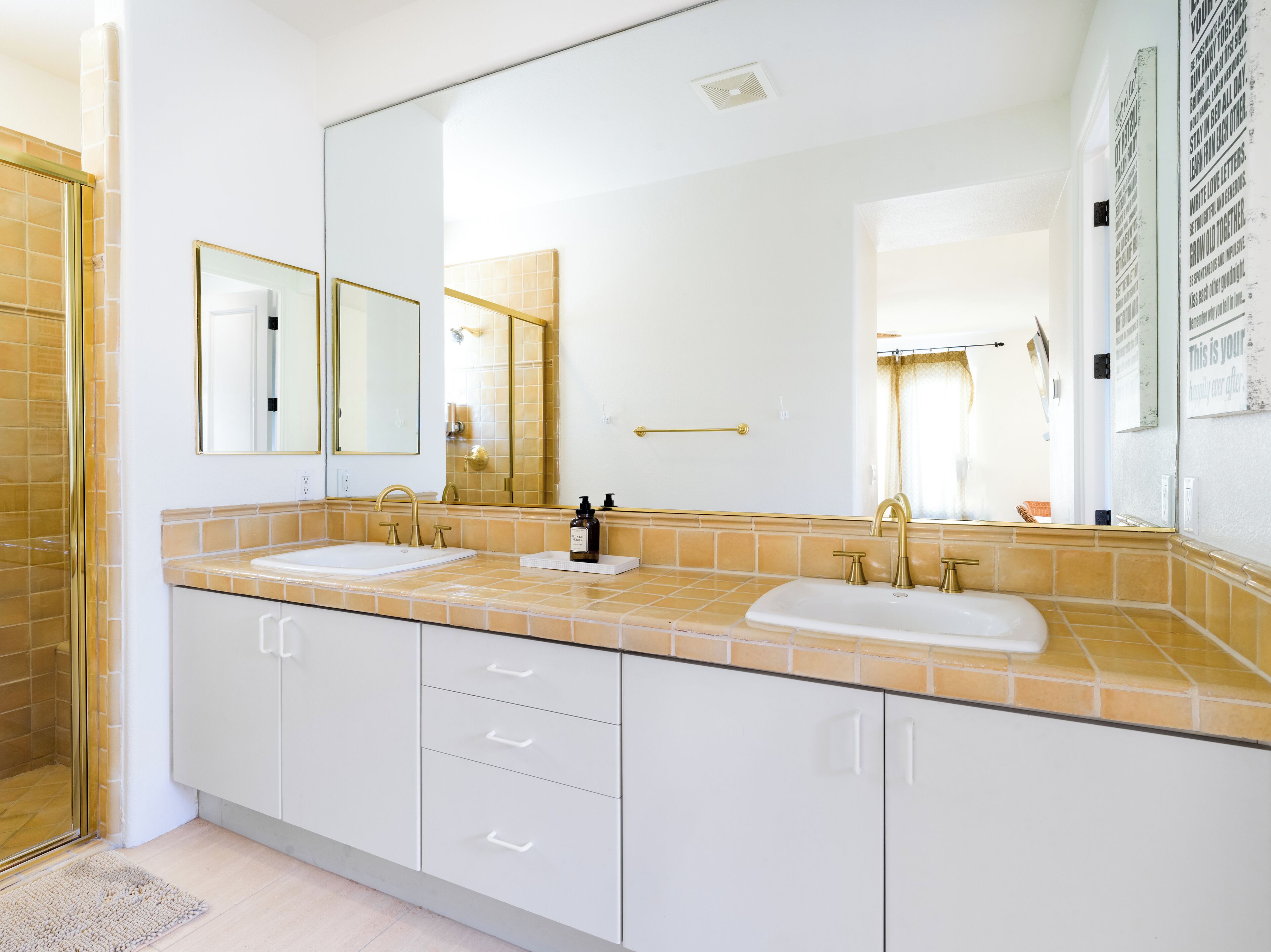A modern bathroom with two sinks, a large mirror, and a shower area.