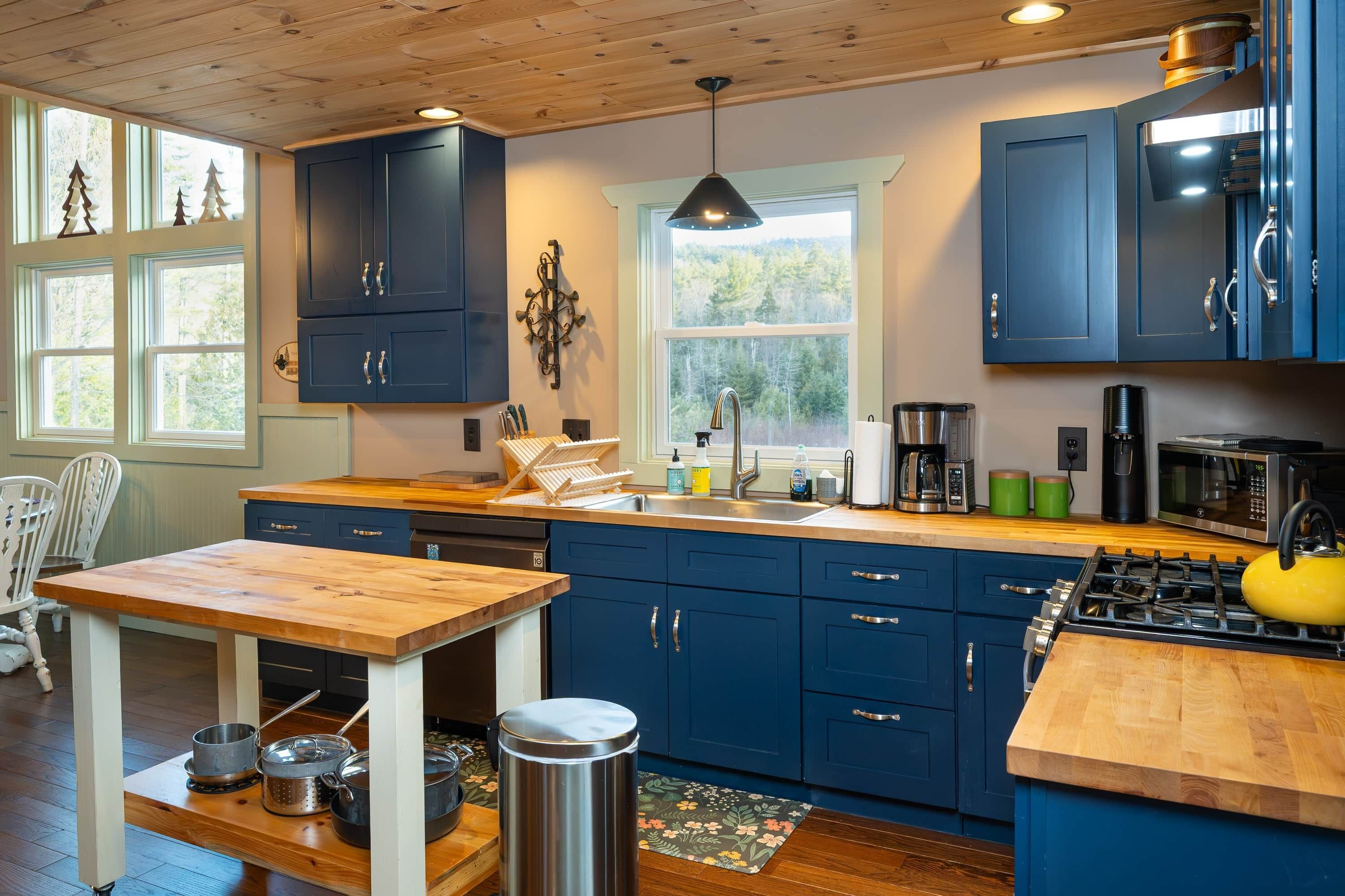 A modern kitchen with wooden cabinets, a sink, a stove, and a dining area with a table.