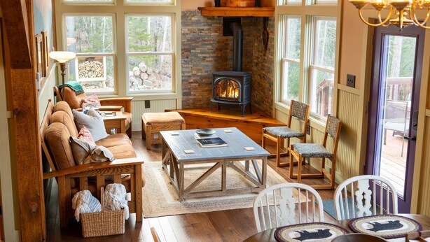 Une pièce chaleureuse avec une cheminée, des meubles en bois et de grandes fenêtres.