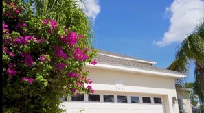 A white building with a garage door, number 303, and a tree with pink flowers. - Sunset villa on Golf Course - Private Pool (Davenport)