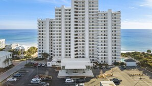 Een hoog hotel met meerdere verdiepingen, een parkeerplaats en uitzicht op de oceaan.