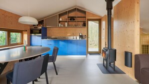 A modern kitchen with blue cabinets, a central island, and a wood-burning stove.