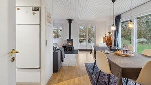 A modern kitchen with a built-in refrigerator, a dining area with a table and chairs, and a large window offering a view of the outdoors. - Cozy home in Gilleleje with kitchen (Gilleleje)