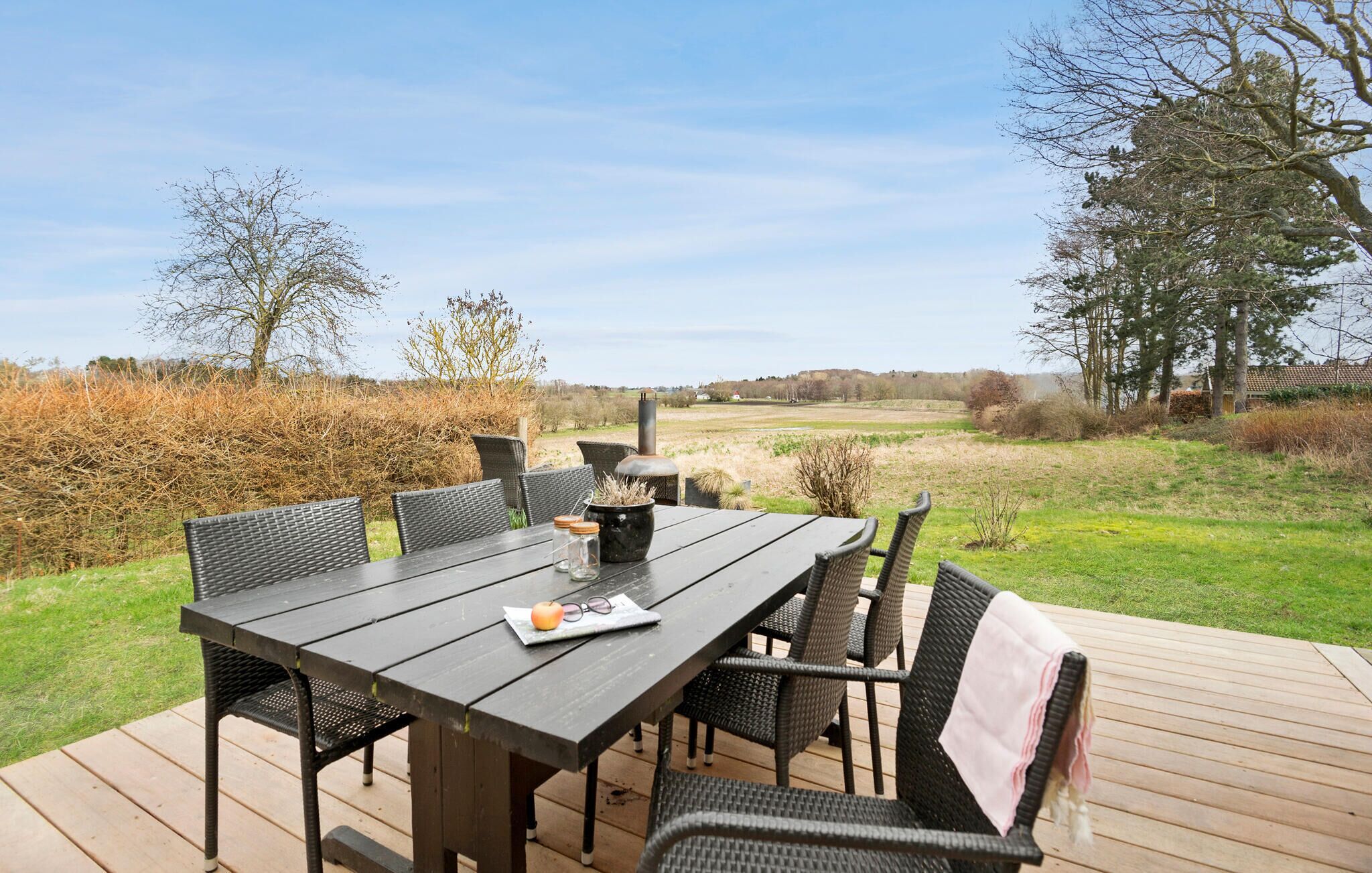 Ein Essbereich im Freien mit Tisch und Stühlen, einem Kamin und Blick auf die Landschaft.