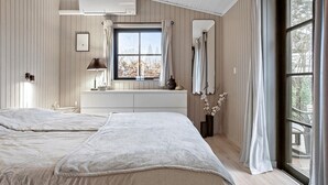 Ein Schlafzimmer mit zwei Betten, einem Vorhangfenster, einem Heizkörper und einer Wandlampe.