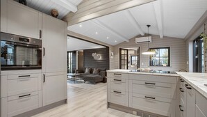 Eine moderne Küche mit integrierten Geräten, ein Essbereich mit einer Couch und ein großes Fenster, das für natürliches Licht sorgt.