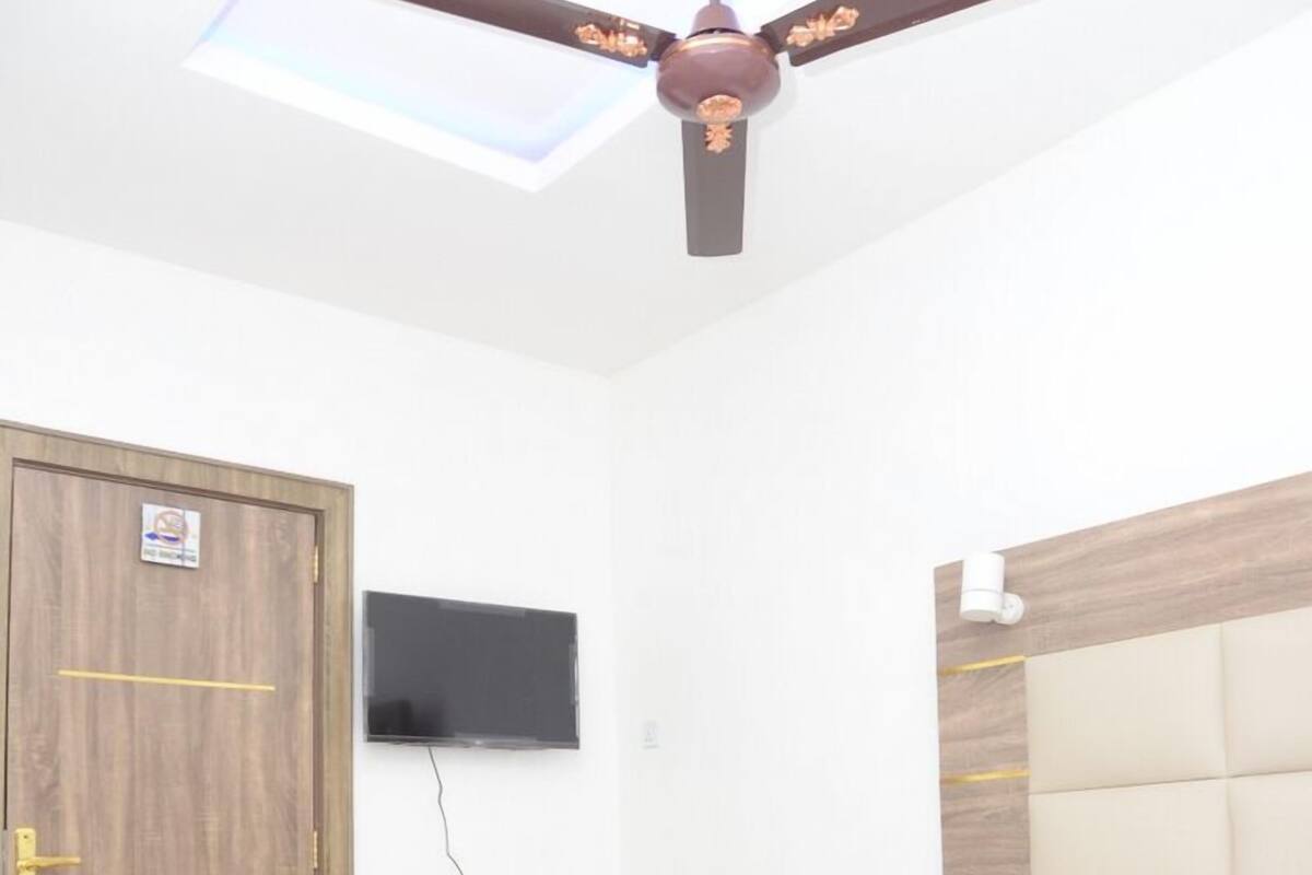 Un dormitorio con cama, armario de madera, televisor de pantalla plana y ventilador de techo.