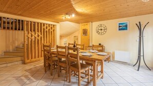 A wooden dining area with a table set for four, a clock, and a radiator. - LA Piemontaise - LE Tsozal (AUSSOIS)