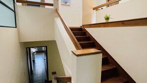 A multi-level staircase with wooden handrails and a potted plant on the upper landing. - The Rainier Bed & Breakfast (San José)