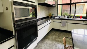 A modern kitchen with white cabinets, a black stove, and a large window. - The Rainier Bed & Breakfast (San José)