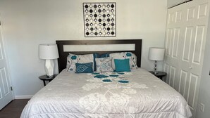 A neatly made bed with a floral-patterned bedspread and blue accents, flanked by two bedside lamps on matching nightstands.