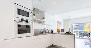 Una cocina moderna con electrodomésticos integrados, un felpudo gris en la entrada y vistas al exterior.
