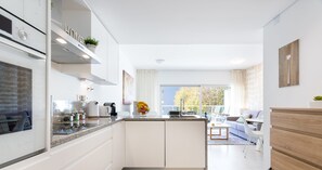 Une cuisine moderne avec des meubles blancs, un îlot central et un coin repas comprenant un canapé et des chaises.