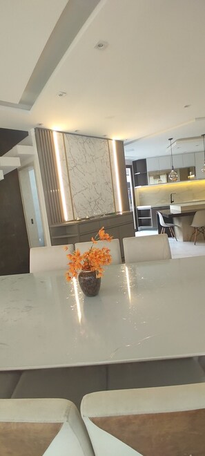 A modern kitchen with a marble backsplash, a dining area with a white table, and a kitchen island with a built-in sink.