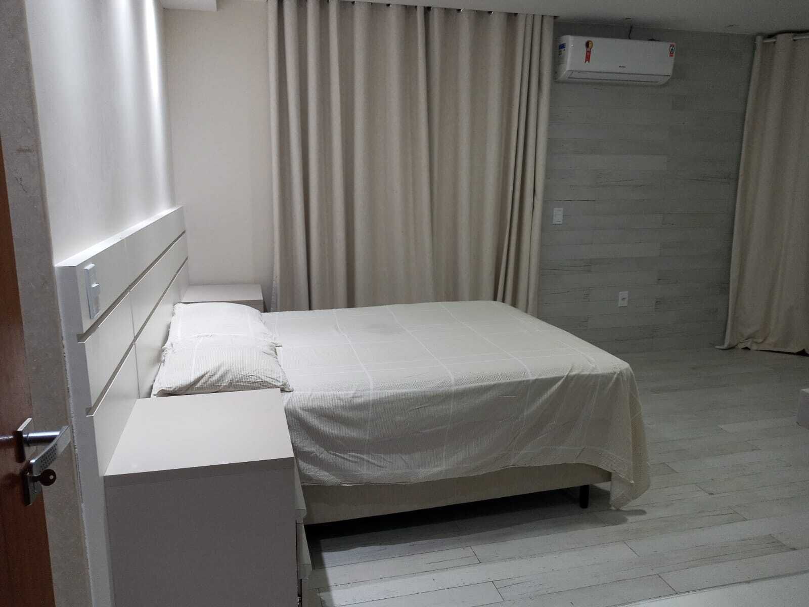 A bedroom with a bed, a bedside table, a wardrobe, and a wall-mounted air conditioning unit.
