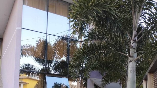 Un bâtiment moderne doté de grandes fenêtres en verre qui reflètent l’environnement.