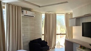 Une chambre d’hôtel moderne équipée d’un grand lit, d’un bureau, d’une chaise, d’une télévision et d’un appareil de climatisation.