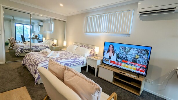 Une chambre d’hôtel avec deux lits, une télévision, un canapé, un bureau et un miroir.