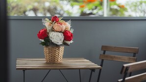 Un panier en osier contenant un bouquet de fleurs, posé sur une table en bois.