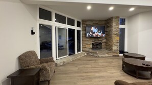 A modern living room with a stone fireplace, large windows, and comfortable seating. - Modern Luxury 3BR Condo Steps Away from Deer Valley Resort w/ Hot Tub, Fireplace (Park City)
