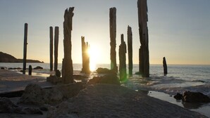 Une plage avec des poteaux en bois et des rochers.