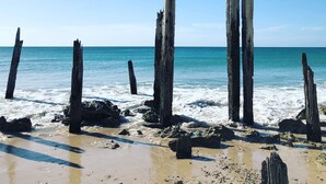 Une plage avec des poteaux en bois et des rochers.
