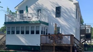 A white two-story house with a balcony, a small porch, and a green awning.