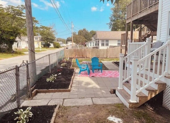 A fenced backyard with raised garden beds, a wooden deck, and a staircase leading to a porch.