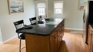 A kitchen with a central island, wooden cabinets, and two windows.
