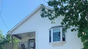 A two-story white house with a balcony on the upper floor, a covered front porch, and a fenced yard.