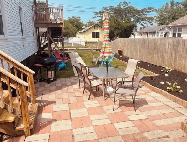 Un patio con una mesa y sillas, un paraguas colorido y una terraza de madera.