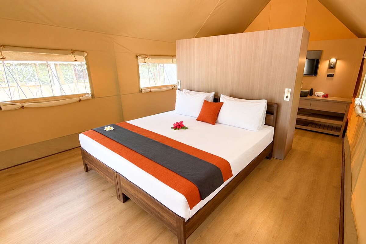 A spacious bedroom with a large bed, a wooden headboard, and a small seating area.