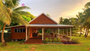 A single-story house with a porch, surrounded by a well-maintained lawn and palm trees. - Mai Sunset Beach Resort (Naviti Island)