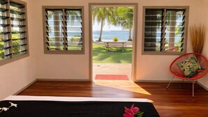 A bedroom with a bed, a view of the ocean, and a chair with a cushion. - Mai Sunset Beach Resort (Naviti Island)