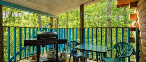 An outdoor wooden deck with a barbecue grill, chairs, and a table.