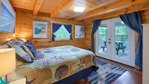 Interno di una baita in legno con un letto, un quadro e vista dalla porta.