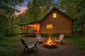 Eine Blockhütte mit Feuerstelle und Sitzgelegenheiten im Freien.