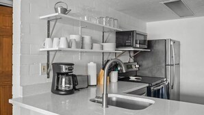 A modern kitchen with white countertops, a stainless steel sink, a coffee maker, a microwave, and a refrigerator. - Prospector Place - 2(King)Bed 2Bath - Easy to ski! (Park City)