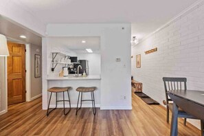 Una cocina moderna con armarios blancos, estufa integrada y dos taburetes de bar.