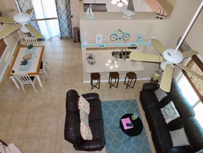 A modern living room with a black leather sofa, a dining area with a white table, and a kitchen area with a central island. - Sunset Beach Getaway minutes away from PARADISE!! (Englewood)