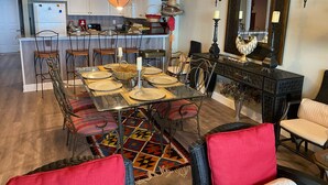 Un coin repas avec une table en verre, des chaises en métal et un tapis à motifs.